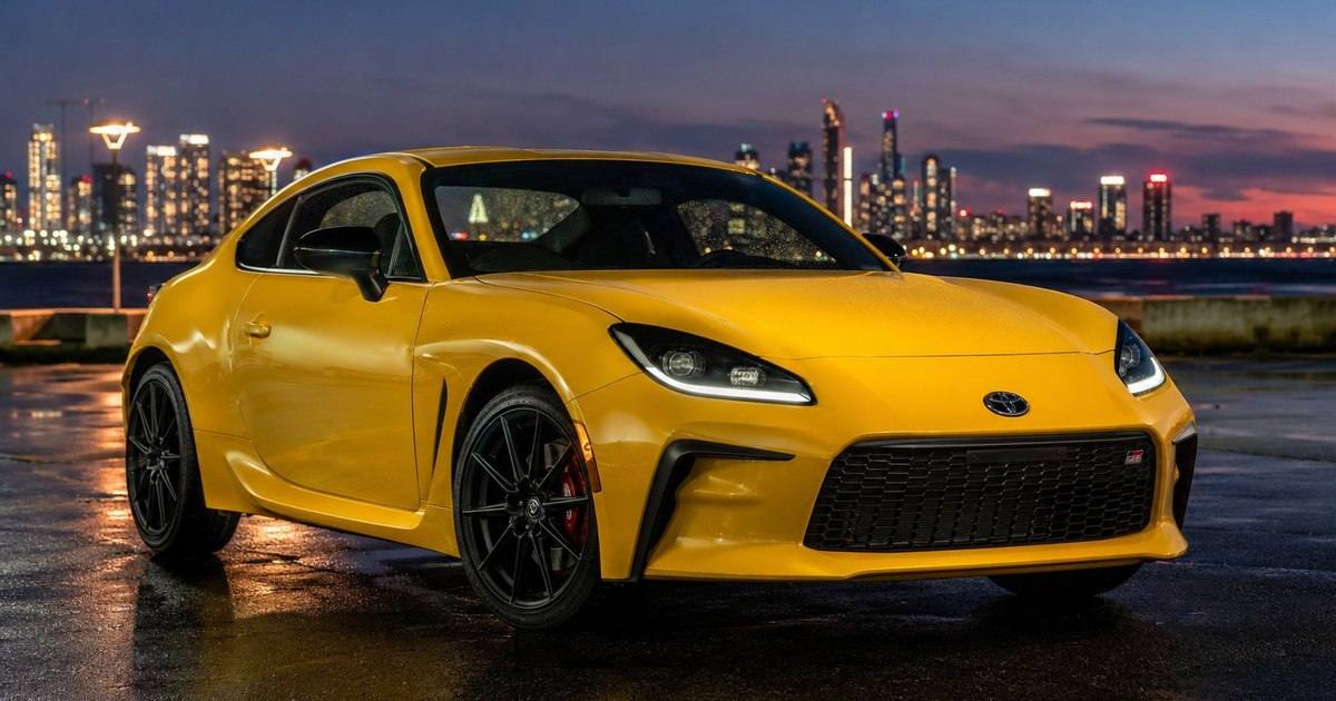 2026 Toyota GR86 Yuzu Edition parked at dusk with a city skyline behind it
